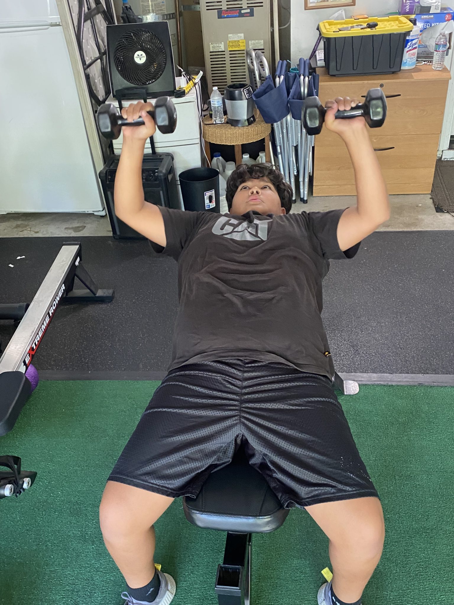 A young athlete pressing dumbbells on a bench