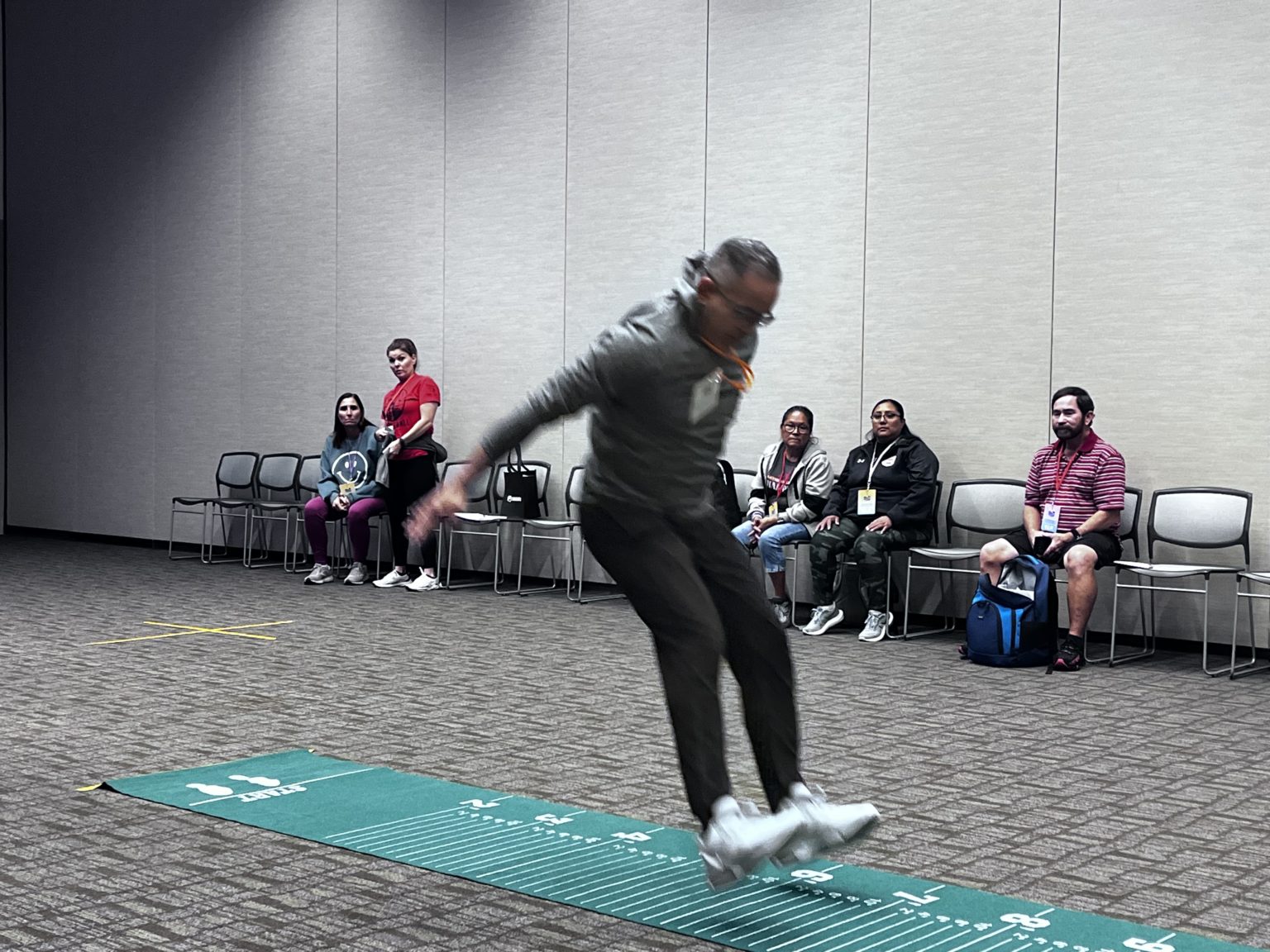Broad jump demonstration on a measuring mat at a clinic