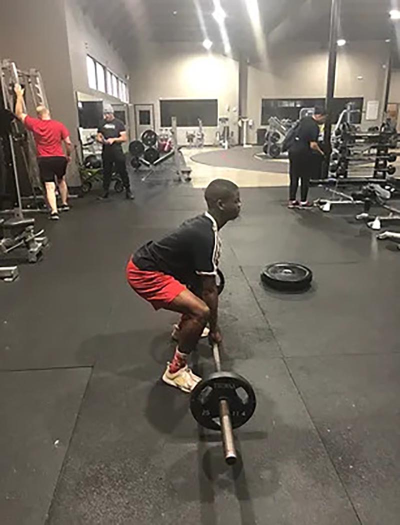 A young athlete setting up for a deadlift during a sports prep session